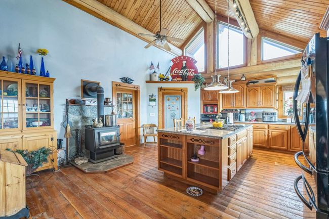 Kitchen featuring open shelves, wood ceiling with exposed beams, a wood stove, freestanding refrigerator, and light wood-type flooring | Image 28