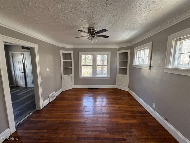 Dinig Room featuring visible vents, a ceiling fan, wood-type flooring, a textured ceiling, and built in shelves | Image 6
