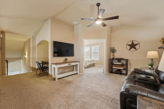 Carpeted living area with ceiling fan, vaulted ceiling, and visible vents | Image 32