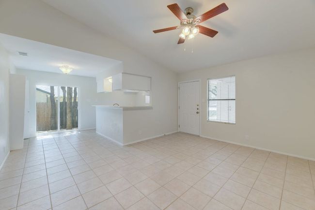 Unfurnished living room with plenty of natural light, vaulted ceiling, a ceiling fan, light tile patterned flooring, and baseboards | Image 10