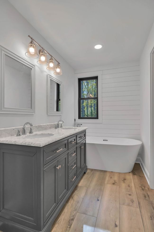 Nice double vanity with tub, ship lap accent wall, LVP waterproof flooring, new lighting, and mirrors. | Image 23