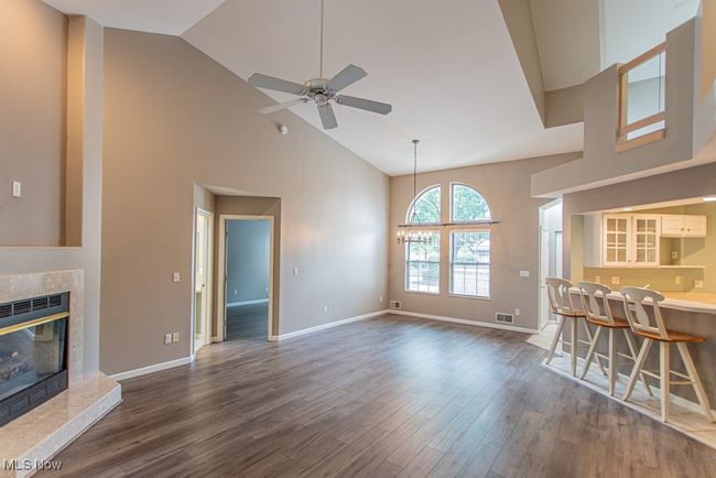 Living area with a premium fireplace, high vaulted ceiling, dark wood-style floors, a ceiling fan, and a chandelier | Image 18
