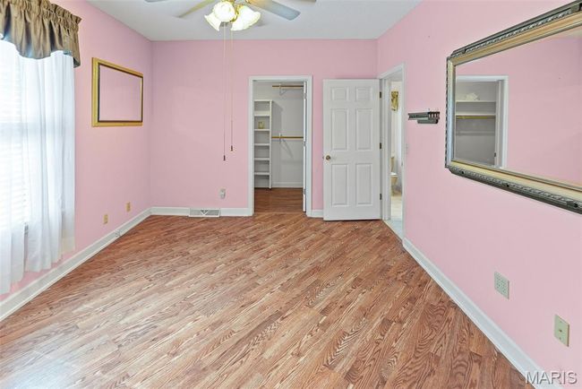 Unfurnished bedroom featuring light wood-type flooring, a spacious closet, a ceiling fan, and a closet | Image 29
