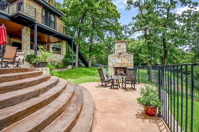 View of patio featuring a balcony and an outdoor stone fireplace | Image 2