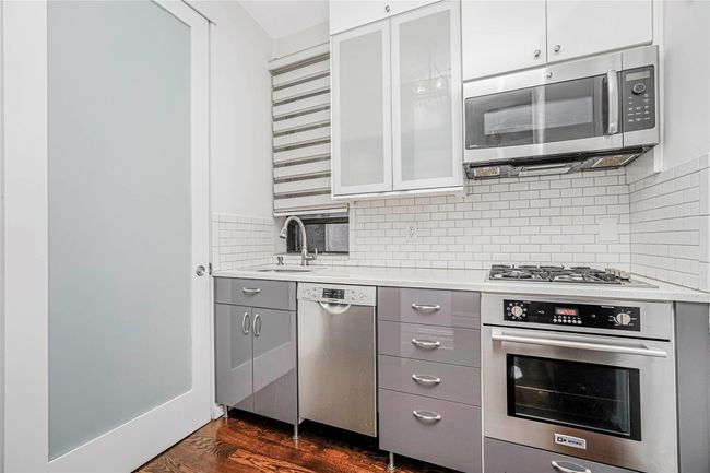 Kitchen featuring appliances with stainless steel finishes, gray cabinets, light countertops, tasteful backsplash, and glass insert cabinets | Image 12