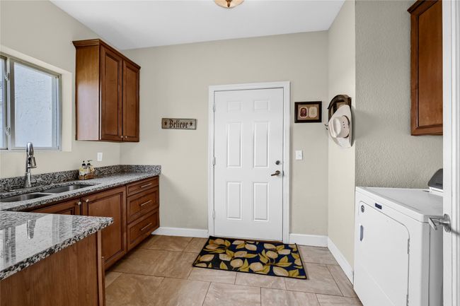 Washroom with cabinets, light tile patterned floors, washer / clothes dryer, and sink | Image 26