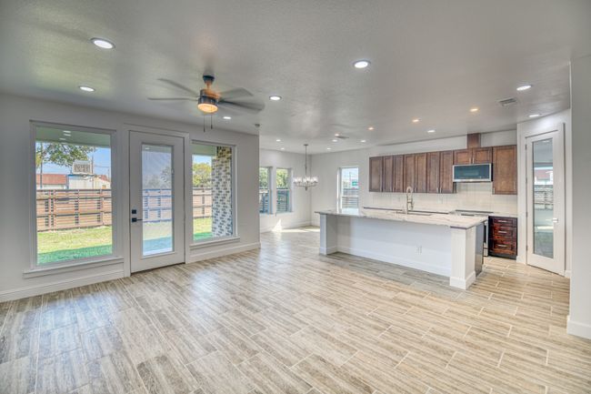 Kitchen featuring a healthy amount of sunlight, stainless steel appliances, a center island with sink, and a kitchen bar | Image 9