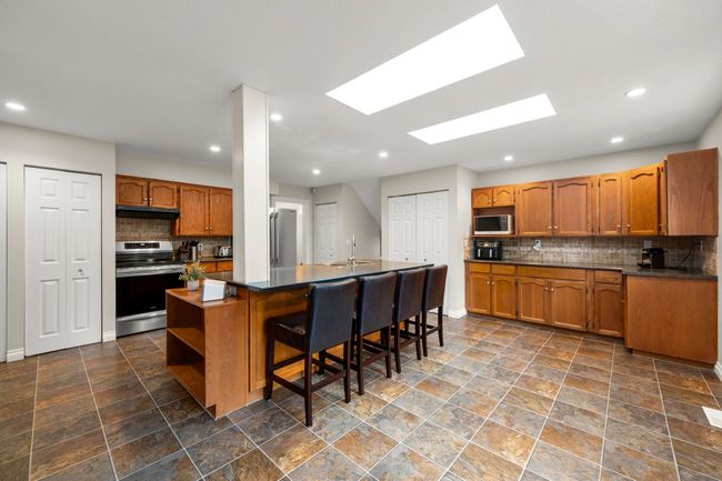 Kitchen with a sink, open shelves, brown cabinetry, and appliances with stainless steel finishes | Image 14