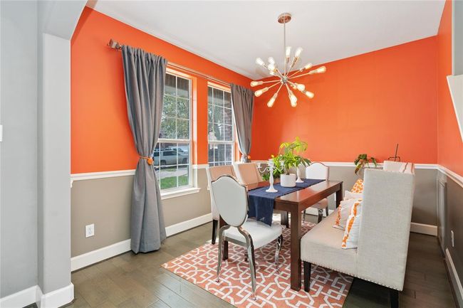 Bright dining room with bold orange walls, modern chandelier, and large windows. Features a stylish table, cushioned seating, and a patterned rug for a cozy, contemporary feel. | Image 9