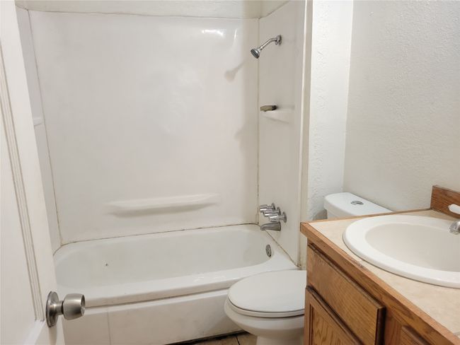 Full bathroom with toilet, vanity, shower / washtub combination, and a textured wall | Image 12