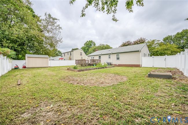 Fenced backyard featuring a vegetable garden, a shed, and a deck | Image 22