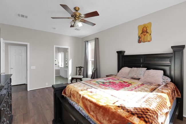 Bedroom with dark wood-style floors, ensuite bath, visible vents, and a ceiling fan | Image 17