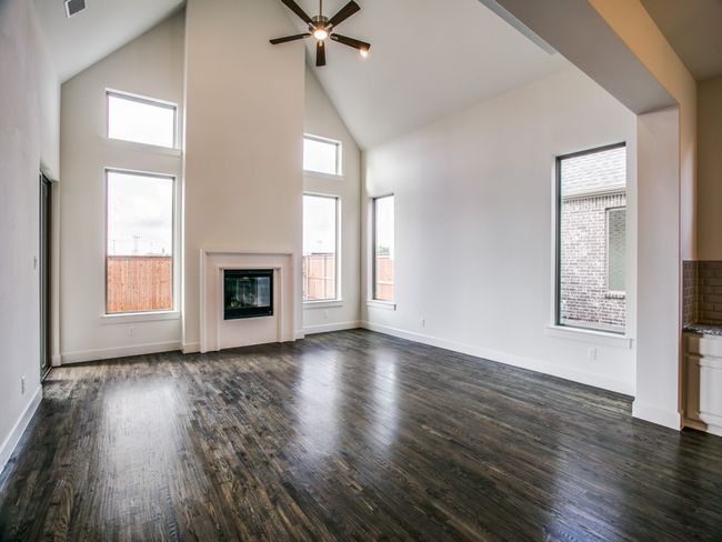 Unfurnished living room featuring high vaulted ceiling, ceiling fan, dark wood finished floors, and a glass covered fireplace | Image 7