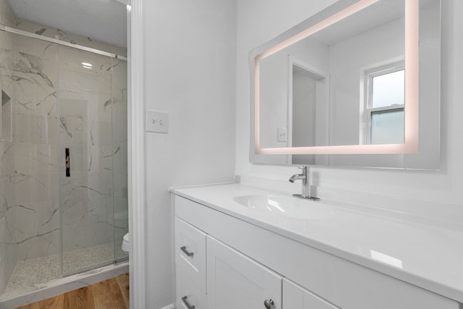 Full bathroom featuring a marble finish shower, vanity, and wood finished floors | Image 24