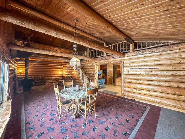 Unfurnished dining area with carpet floors, a wood stove, vaulted ceiling with beams, and wood ceiling | Image 28