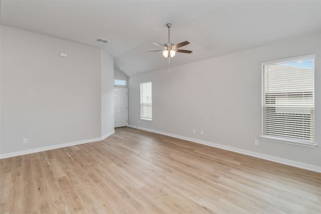Unfurnished room featuring visible vents, light wood-style flooring, a ceiling fan, vaulted ceiling, and baseboards | Image 9