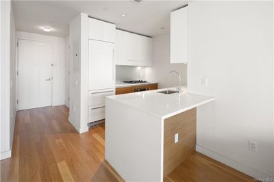 Kitchen with light hardwood / wood-style flooring, kitchen peninsula, sink, gas cooktop, and white cabinets | Image 2