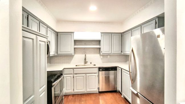 Kitchen featuring sink, light hardwood / wood-style flooring, gray cabinets, stainless steel appliances, and backsplash | Image 7
