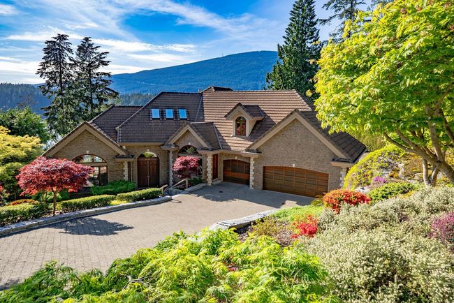 View of front of house with stone siding, a garage, decorative driveway, and a mountain view | Image 10