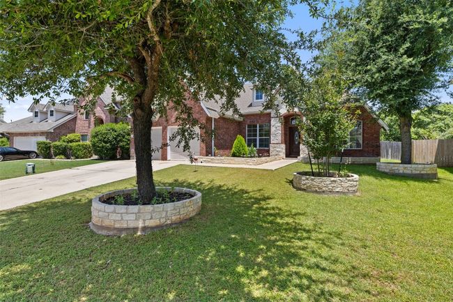 View of property hidden behind natural elements with concrete driveway, an attached garage, and brick siding | Image 5