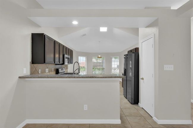 Breakfast bar divides the dining area and the kitchen. | Image 16