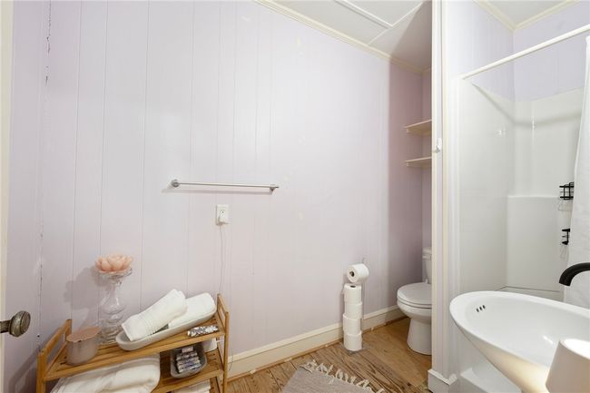 Full bath featuring wood finished floors, toilet, a shower, ornamental molding, and baseboards | Image 39