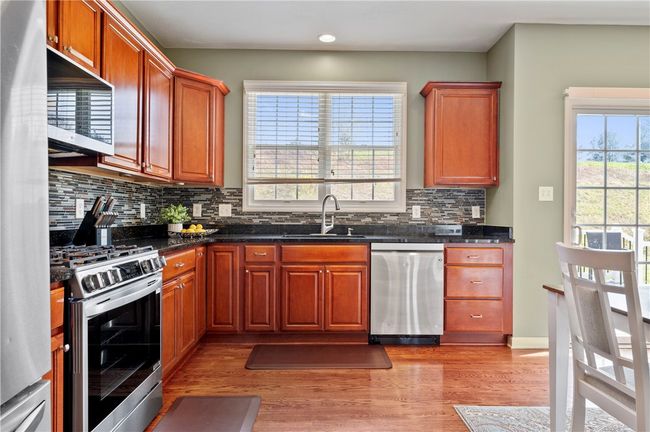 The kitchen offers newer stainless appliances, granite countertops and a tile backsplash. | Image 5