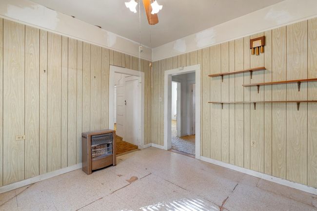 Empty room with wooden walls, baseboards, a ceiling fan, and heating unit | Image 19