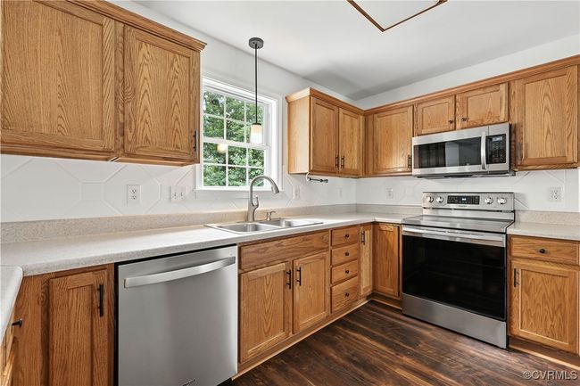 Kitchen featuring appliances with stainless steel finishes, decorative light fixtures, and light countertops | Image 10