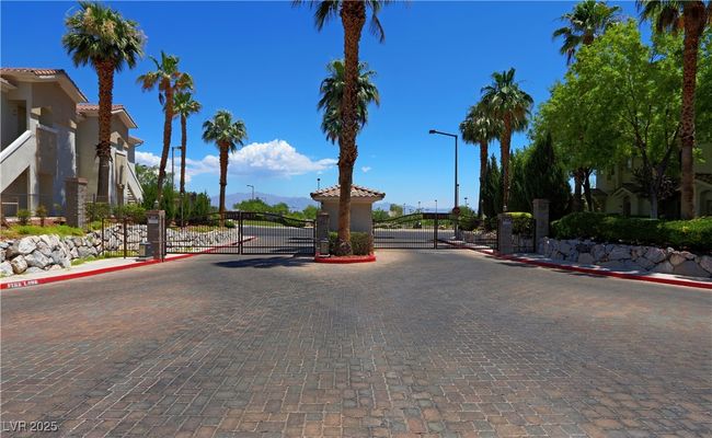 View of decorative road with a gate, curbs, a gated entry, and street lights | Image 25