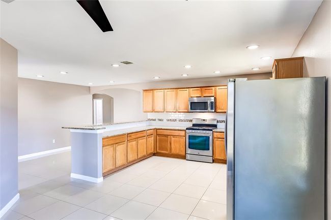 Kitchen featuring appliances with stainless steel finishes, a peninsula, arched walkways, light stone countertops, and recessed lighting | Image 13