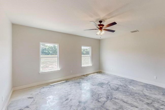Empty room with unfinished concrete floors, visible vents, baseboards, and a ceiling fan | Image 16