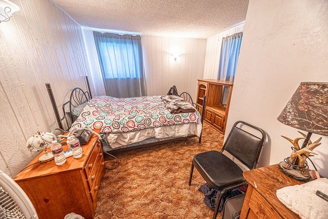Bedroom featuring carpet floors, wood walls, and a textured ceiling | Image 47