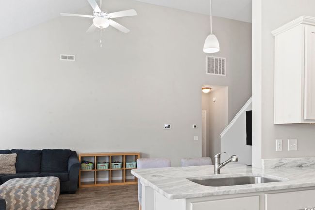 Kitchen featuring visible vents, a sink, white cabinetry, and high vaulted ceiling | Image 14