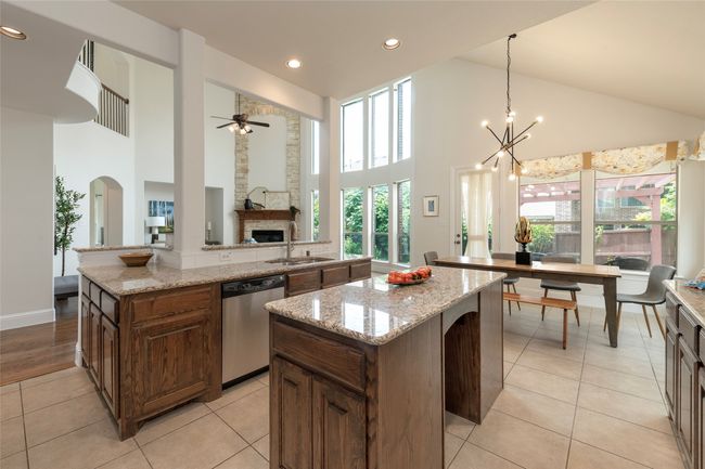 Kitchen with dishwasher, a center island, high vaulted ceiling, a ceiling fan, and a fireplace | Image 14