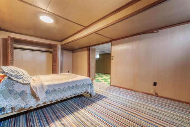 Bedroom with a closet, carpet, wood ceiling, and wooden walls | Image 31