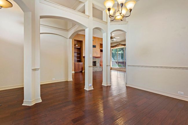 Unfurnished living room with arched walkways, hardwood / wood-style floors, a brick fireplace, and baseboards | Image 30