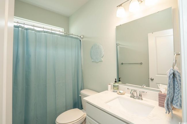 Bathroom featuring toilet, vanity, and curtained shower | Image 14