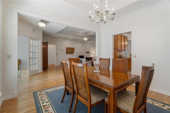 Dining room featuring ornamental molding, light wood-style flooring, baseboards, and ceiling fan with notable chandelier | Image 10
