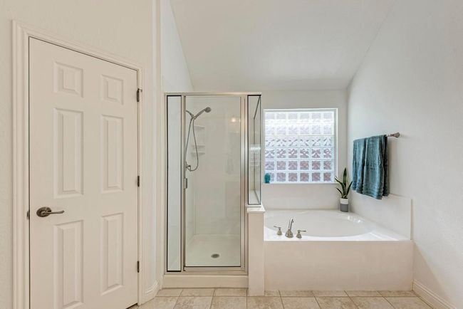 Full bath featuring tile patterned floors, a bath, and a stall shower | Image 25