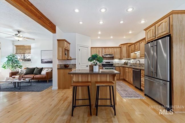 Kitchen with appliances with stainless steel finishes, open floor plan, a center island, decorative backsplash, and beamed ceiling | Image 19