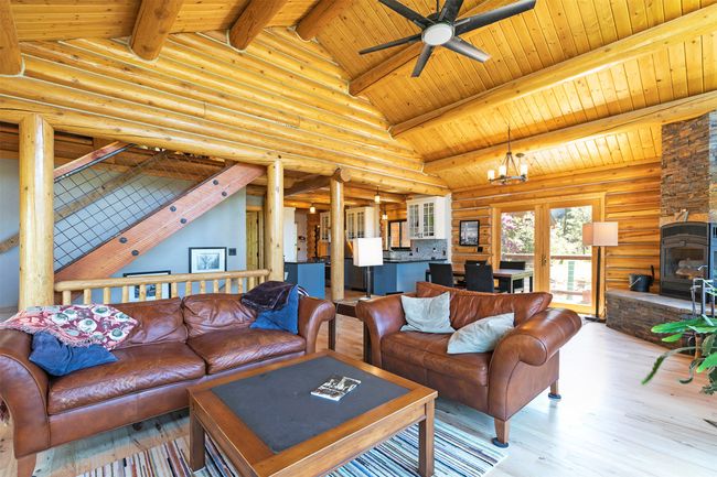 Living area with wood finished floors, a ceiling fan, wood ceiling, rustic walls, and french doors | Image 17