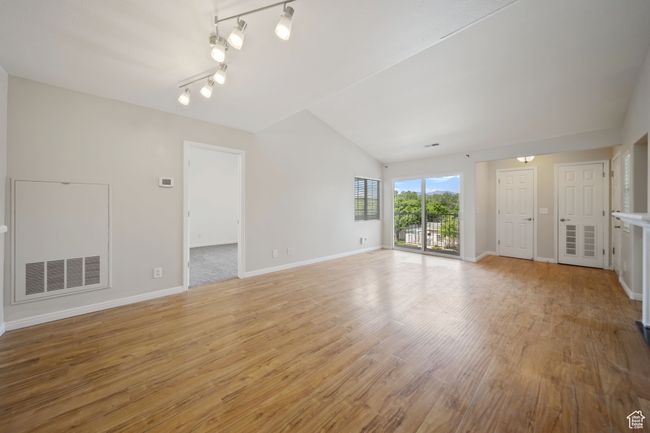 Unfurnished living room with light wood finished floors and vaulted ceiling | Image 4