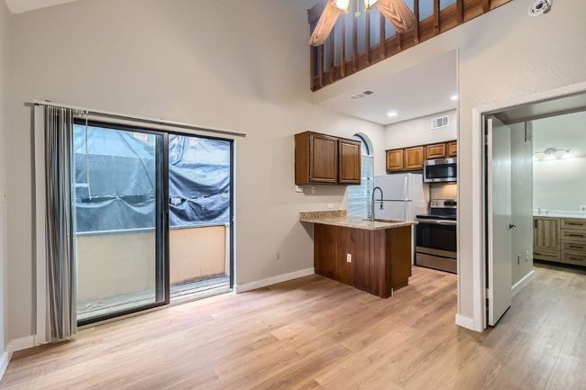 Kitchen with visible vents, light wood-style flooring, appliances with stainless steel finishes, and a peninsula | Image 6
