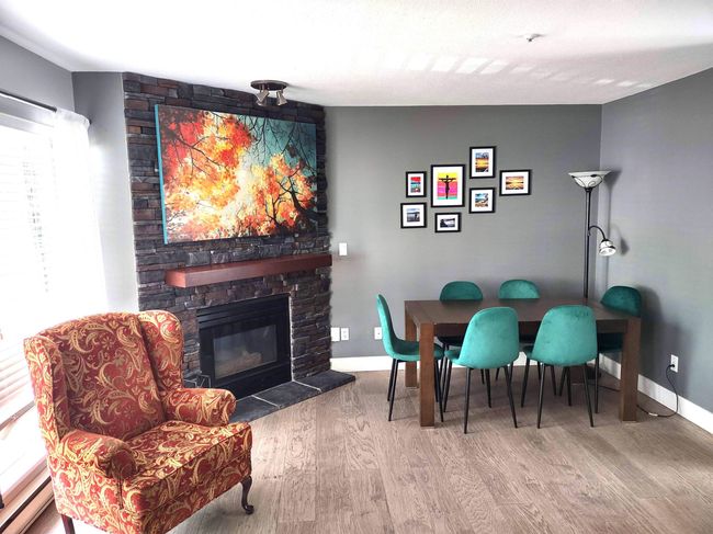Dining room with a fireplace, a baseboard radiator, baseboards, and wood finished floors | Image 5
