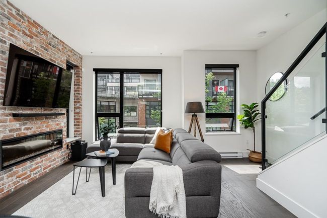 Living area featuring stairs, wood finished floors, a brick fireplace, and a baseboard radiator | Image 11