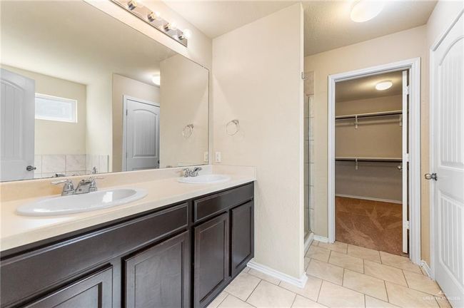 Bathroom with a stall shower, double vanity, tile patterned flooring, and a spacious closet | Image 13