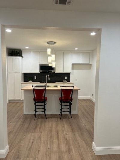 Kitchen with a kitchen breakfast bar, white cabinetry, and light hardwood / wood-style flooring | Image 3