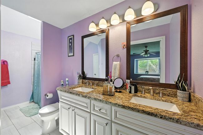 Full bathroom with double vanity, ensuite bathroom, tile patterned floors, a shower with shower curtain, and a ceiling fan | Image 15