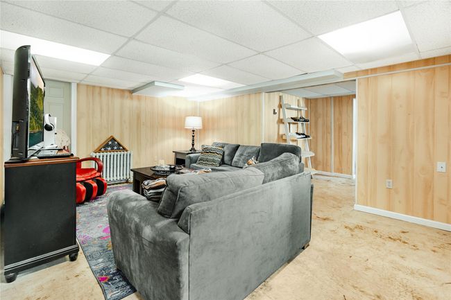 Living area with radiator heating unit, a paneled ceiling, and wood walls | Image 28